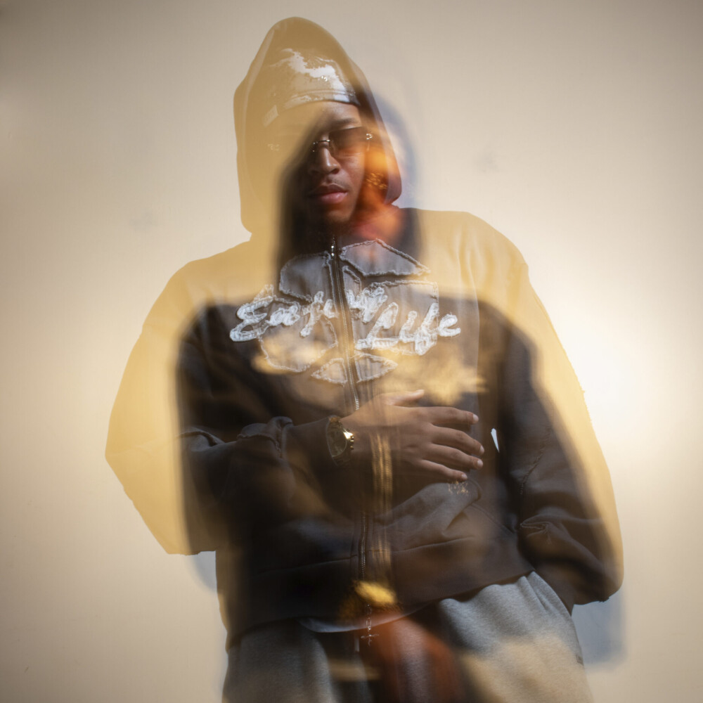 mo beanie stands with his hand on his chest, captured with an after-effect and artistic light treatment.